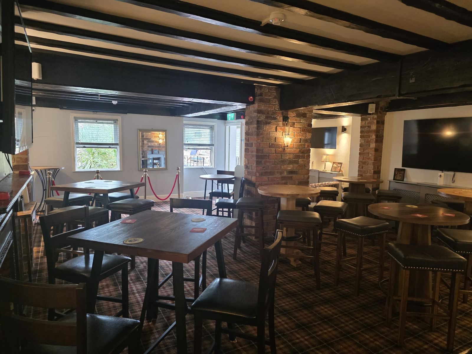 Inside The Nags Head, with exposed black beams, brick pillars and traditional pub tables